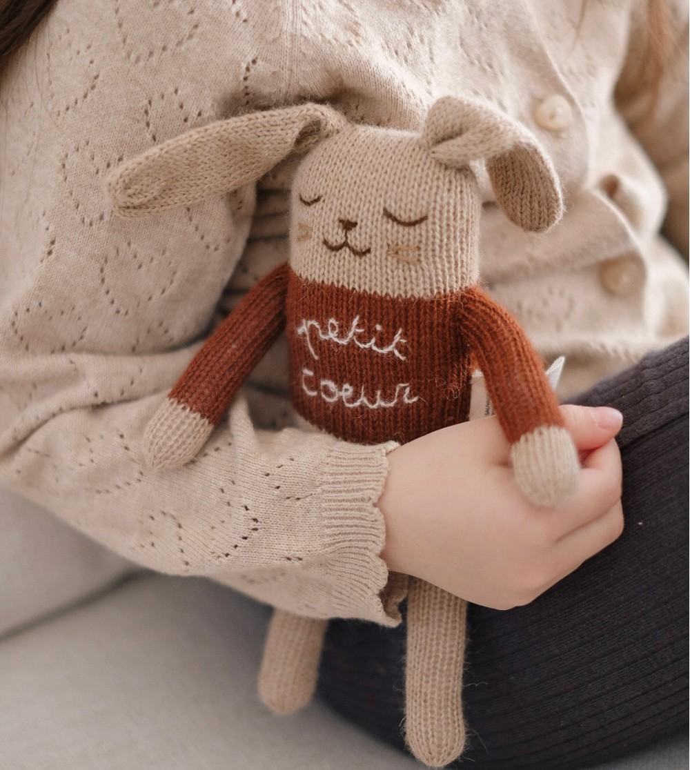 Doudou nouveau né lapin en laine naturelle petit cœur, porté contre bébé.