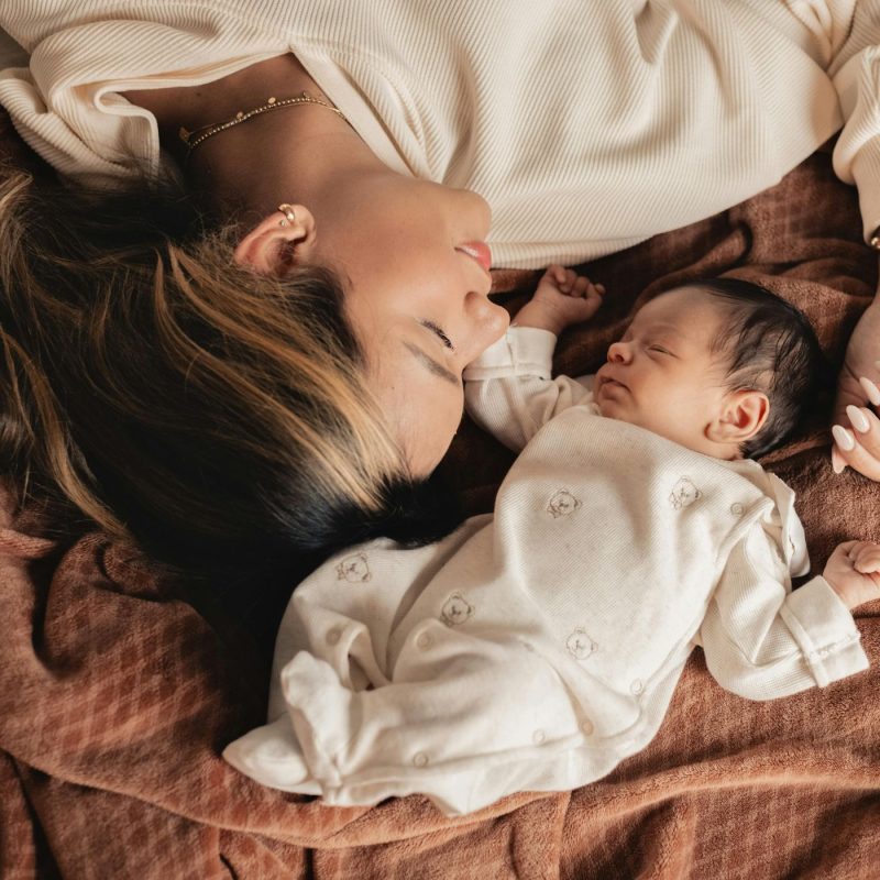 Maman allongée avec son nouveau-né pendant le post-partum, période de récupération avant le retour de couche.